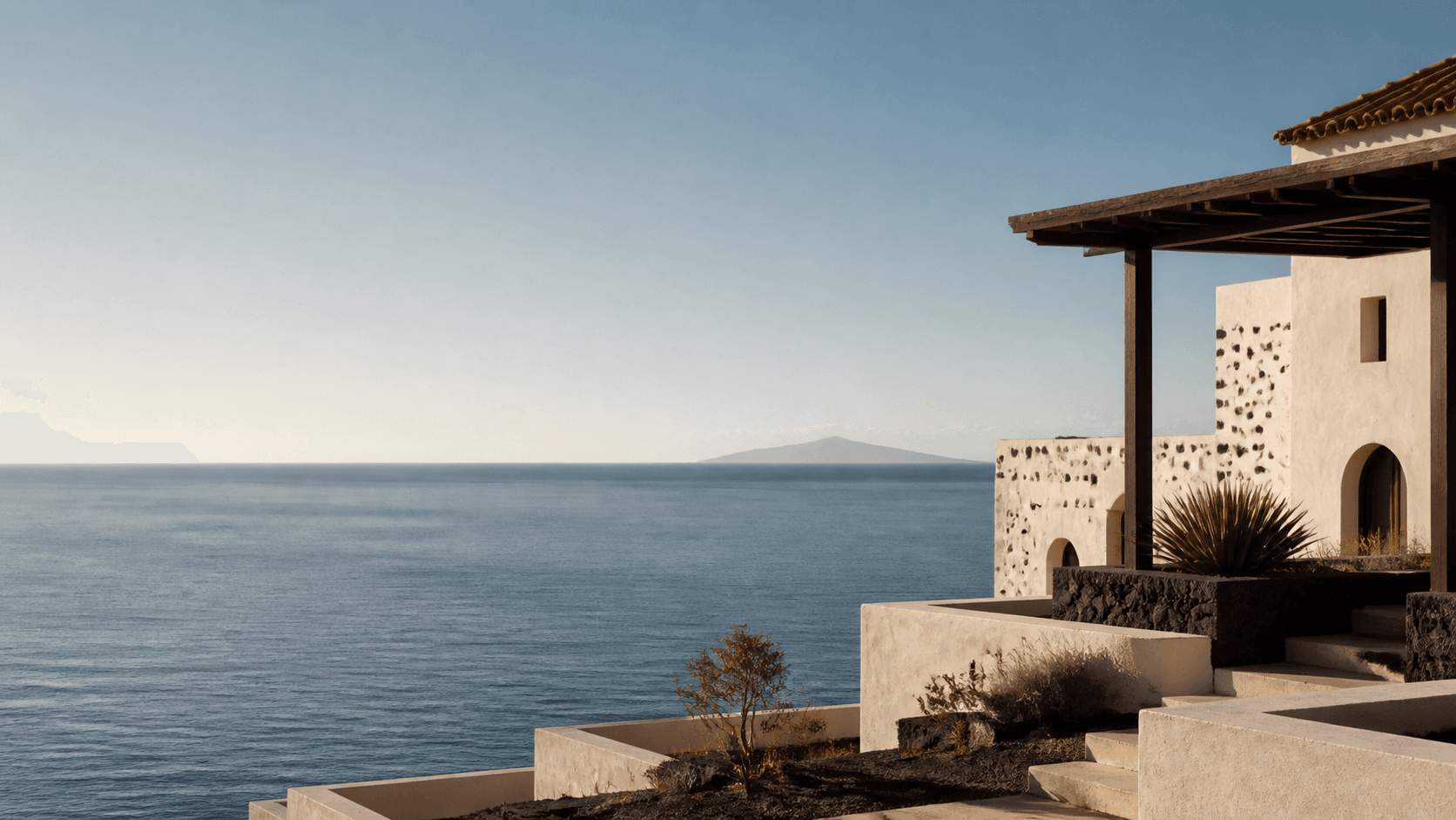 Arquitectura costera de inspiración mediterránea con terrazas de piedra, luz cálida y horizonte marítimo.